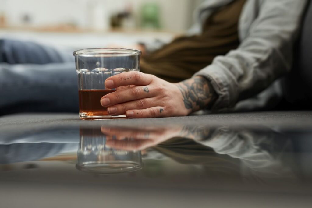 Osoba trzymająca szklankę z alkoholem, mogąca potrzebować różnych rodzajów terapii.