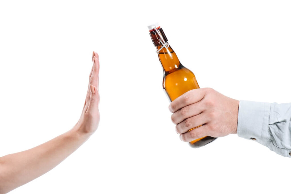 Osoba odmawiająca alkoholu, by uniknąć kosztów terapii.