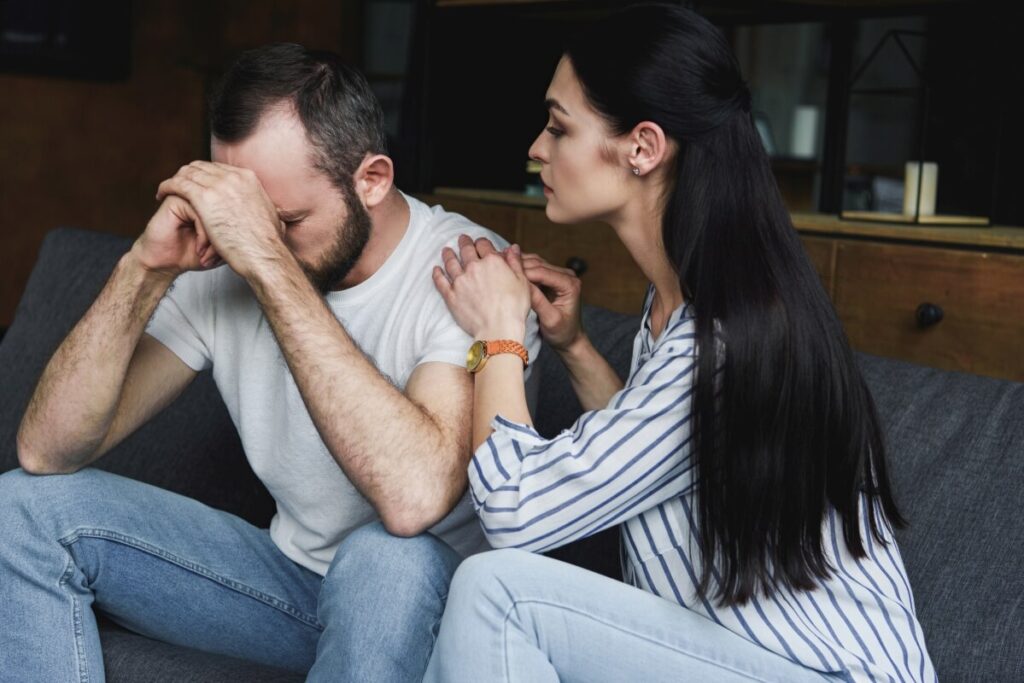 Kobieta pociesza mężczyznę, który zmaga się z problemami, które przypominają mu o możliwości pobytu w zamkniętym ośrodku.