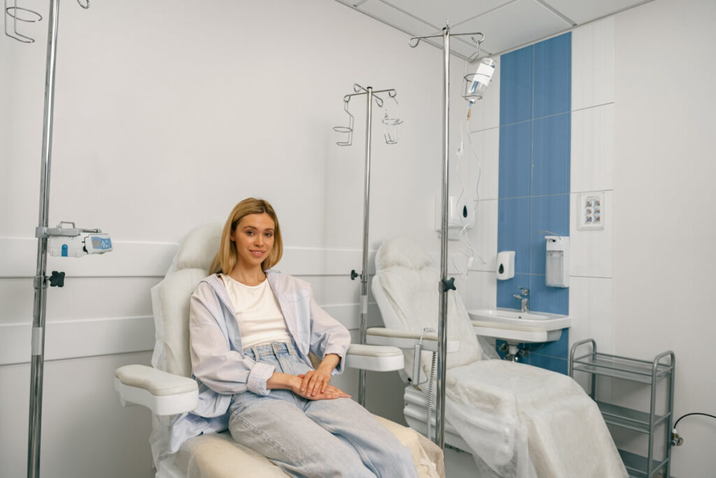 Kobieta siedzi w gabinecie medycznym, prezentując zdrowe paznokcie.