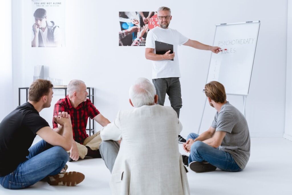 Grupa mężczyzn uczestniczy w dyskusji na temat roli psychoterapii i farmakoterapii.